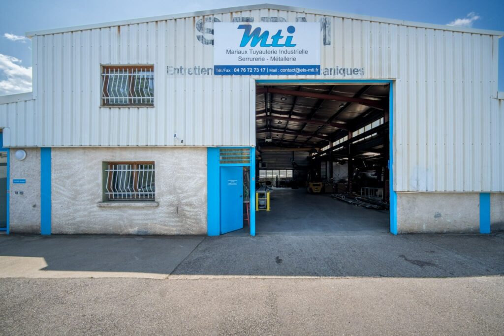Locaux de MTI à Claix avant les travaux, bardage blanc et menuiseries bleues d’origine